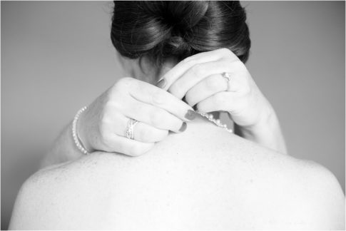 bride putting on necklace black and white