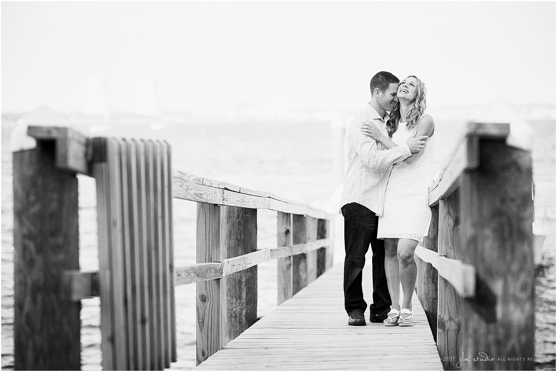 seaside engagement session bride and groom on a dock black and white image
