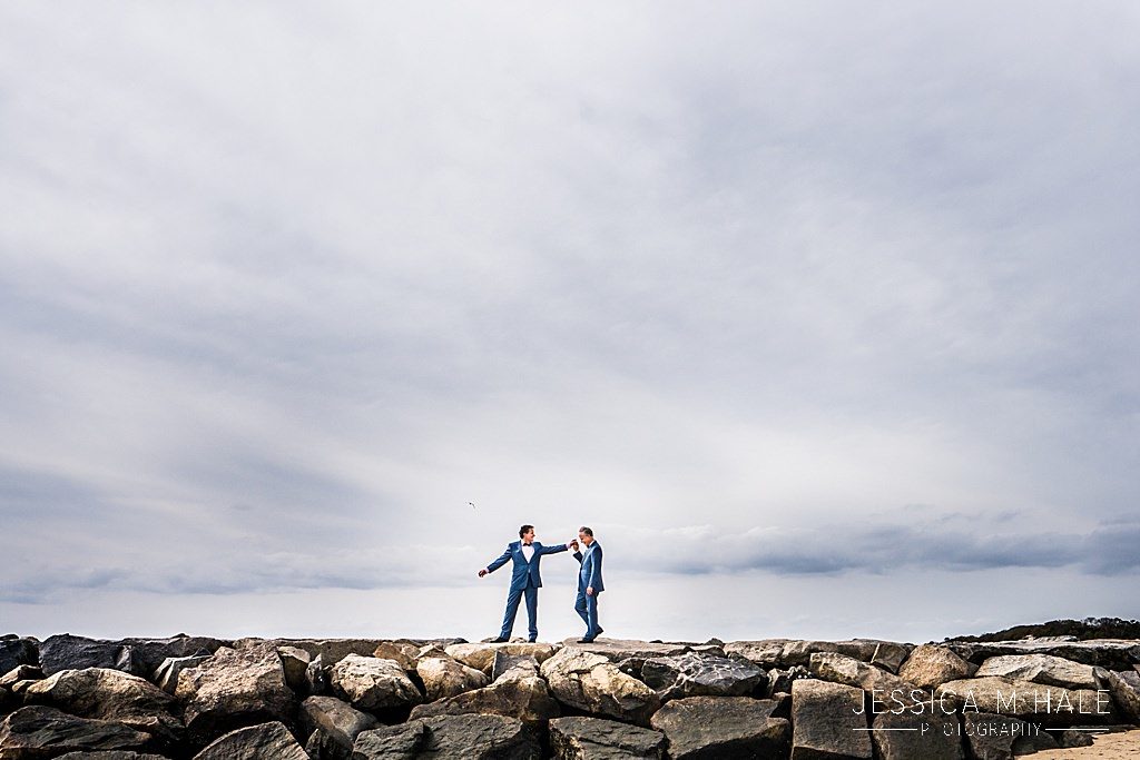 Two grooms hold hands on the Provincetown Causeway.
